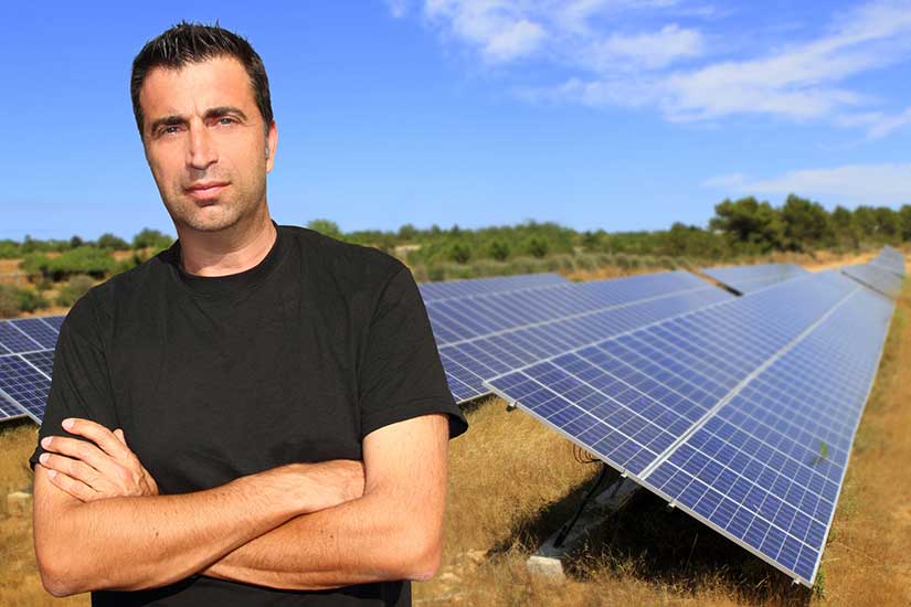 man in front of solar panels in field